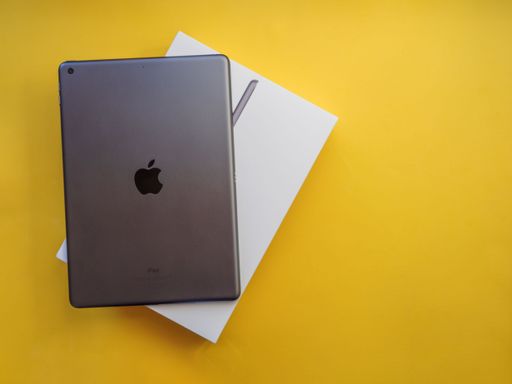 A top view of a gray Apple iPad on a yellow background