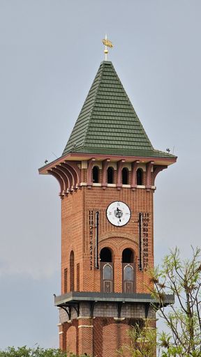 A vertical of a tall clock tower building against a cloudy sky