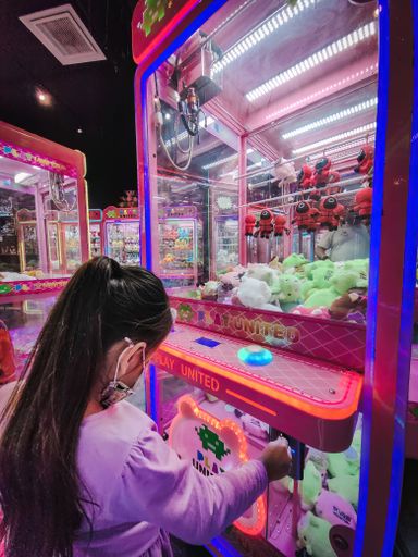 An adorable little girl with having fun attempting to play a classic arcade game machine