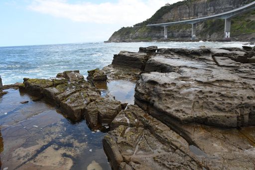 A majestic view of wavy seascape and rocky coastline in Australia at daytime under a cloudy blue sky