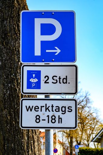 A parking lot sign with additional notes on a limited park duration of two hours on weekdays