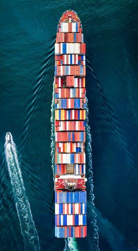 An overhead shot of a large container carrier ship on the water with beautiful textures