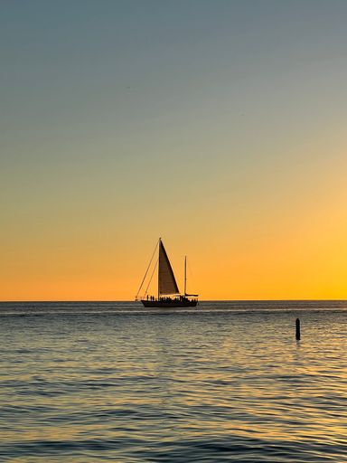 A stunning sailboat illuminated by the warm rays of the sunset