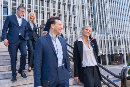 A group of business professionals are walking down a staircase while engaged in a conversation