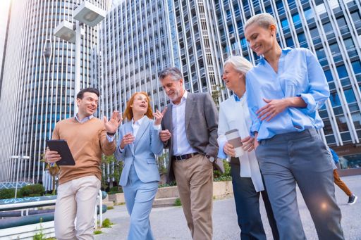 Five business professionals in a cityscape setting, smiling and engaged in conversation