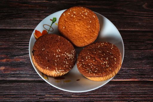 A closeup shot of freshly baked cupcakes with sesame seeds on a porcelain plate on the wooden table