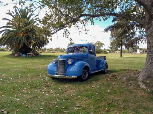 Old blue 1940 Chevrolet Chevy pickup truck hot rod in the countryside under a tree. CAACMACH 2023 classic car show. Copyspace.