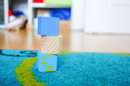Square toys of multiple colors on top of each other on a multicolored carpet
