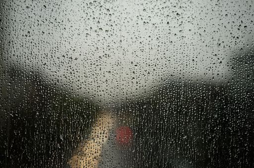 The raindrops on a window pane, with a street light visible in the background