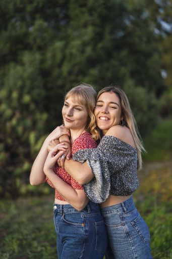 A shallow focus of two young cheerful women hugging in a park in Spain