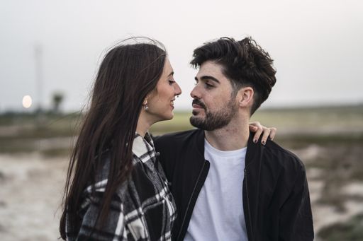 A shallow focus of a young Caucasian couple embracing each other in a field in Spain