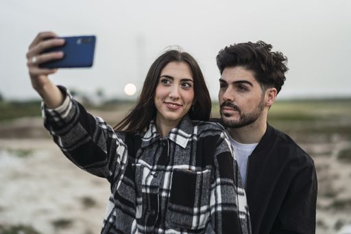 A shallow focus shot of a cute Spanish Caucasian couple taking a selfie outdoors