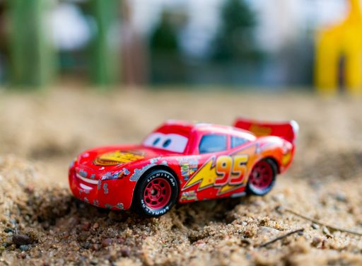 Red Lightning McQueen toy model sport car from the Disney Pixar Cars movie on sand.