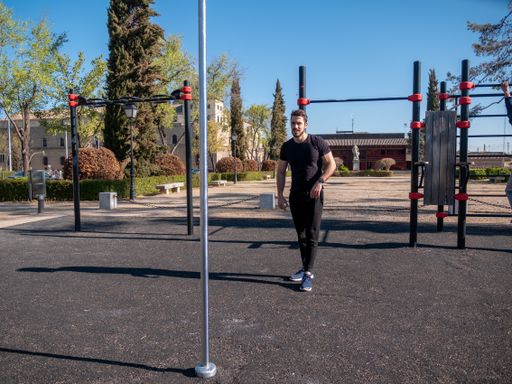 A young Caucasian man doing pole exercises in a park in Toledo, Spain on a sunny spring day