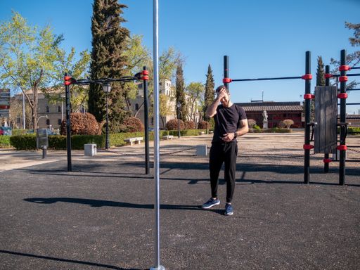 A young Caucasian man doing pole exercises in a park in Toledo, Spain on a sunny spring day