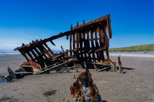 A scenic view of a vintage shipwreck on the Oregon coast near the tranquil body of water