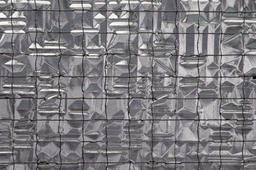 A closeup of a glass mosaic wall with a metallic sheet covering it in a grey and silver color