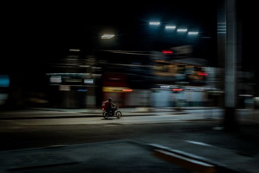 A courier on a delivery  motorcycle on a blurred city background  in the evening