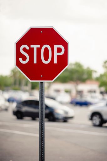 An octagonal red and white stop sign in the foreground of a busy parking lot