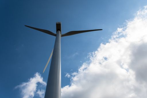A low angle shot of a modern windmill under the sunlight and a blue cloudy sky