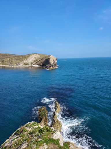 A beautiful landscape of an idyllic beach, featuring a rocky outcrop and towering cliff face overlooking the turquoise waters