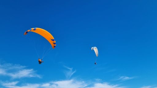 The paragliders soaring in a bright blue sky. Spain.