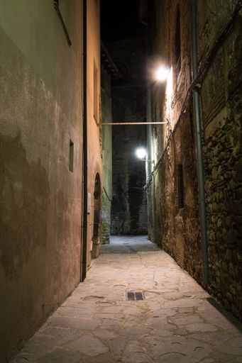 A vertical shot of a narrow pavement passage with brick wall-surface and lights in Barcelona, Spain