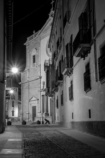 A vertical shot of an empty pavement narrow street near a church in Barcelona, Spain in grayscale