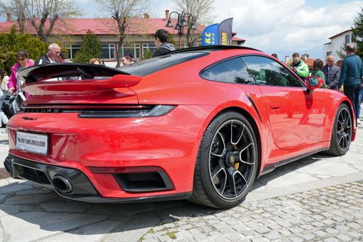 A stunning red Porsche 911 sports car parked on the side of a road, with the sun setting in the background