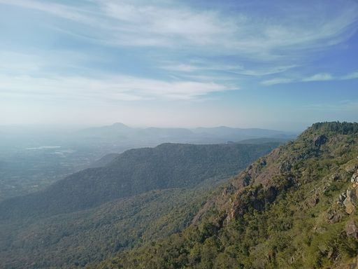 The view of green mountains against the background of a blue cloudy sky.