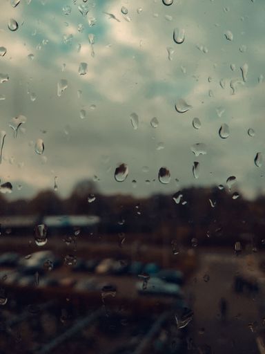 A stunning shot of a window with water droplets, featuring a sunset in the background
