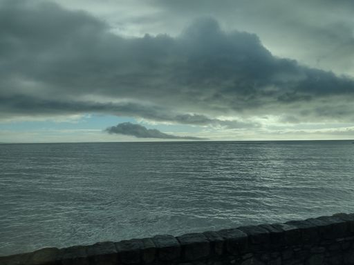 A stunning landscape featuring a body of water with dark storm clouds looming in the background