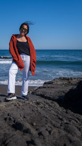 A vertical shot of a beautiful Hispanic woman with on the blue sea background in Chile
