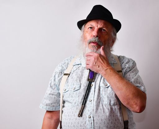 A thoughtful senior Caucasian bearded male in a black hat on white background
