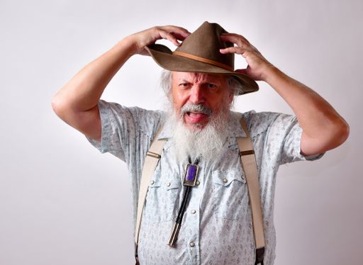 An angry and frustrated senior Caucasian male in a hat on white background