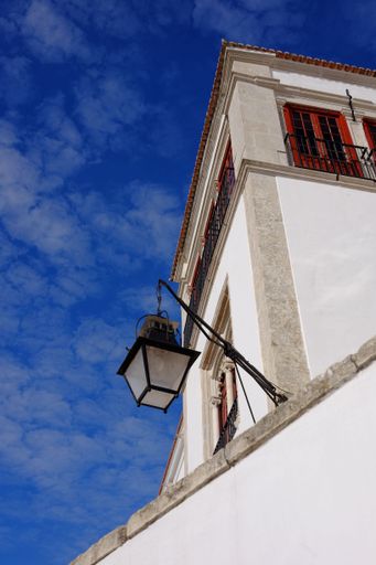 A white-painted building with a street lamp against a blue sky