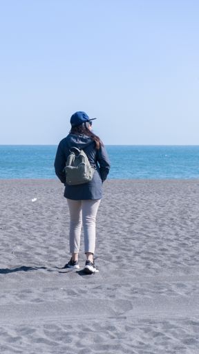 clean image of woman walking on black sand in a chile beach on a sunny day vertical photo chilean girl