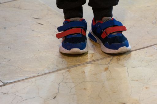 Red and blue sneakers of a child standing on the floor