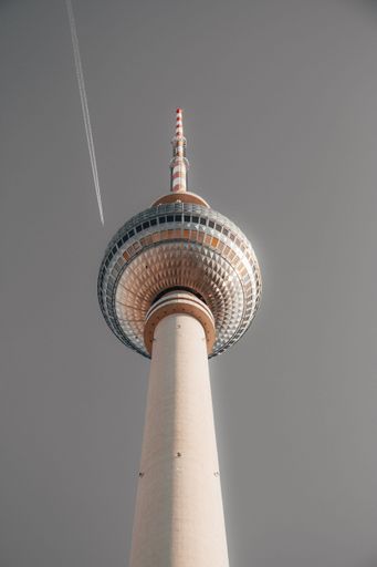 A low angle shot of a beautiful tall white tower in Berlin called Alexanderplatz with a grey sky