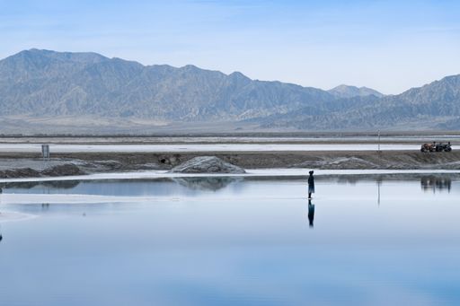 A female standing in shallow water on a beachfront, with a stunning mountainous backdrop