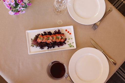 A top view of shrimp with sesame and vegetables served on white tray next to glass of wine and empty plates