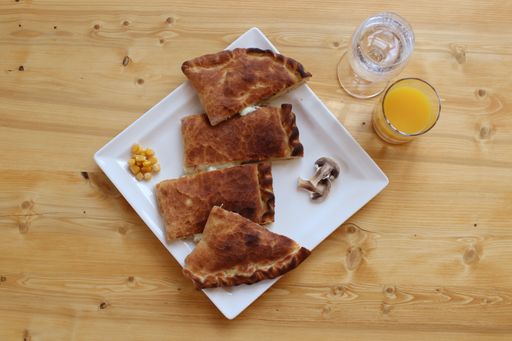 White ceramic plate with cooked pieces of savory pie containing mushrooms and corn, served as a meal or side dish