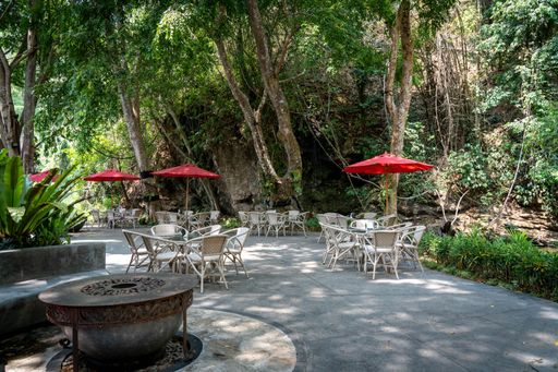 A picture of outdoor patio furniture set in a garden with lush foliage in the background