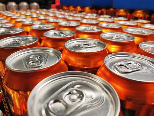 A selective focus shot of shiny orange cans production line at a factory
