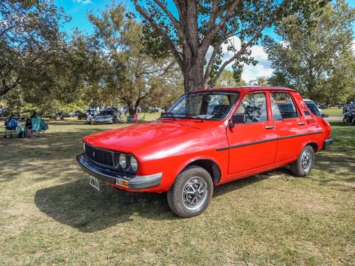 Old red 1988 Renault 12 sedan on the lawn under a tree, the  CAACMACH classic car show 2023