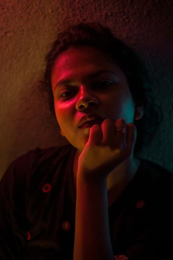 A vertical shallow focus shot of an Indian woman resting her chin on her hand looking at the camera - colorful lights