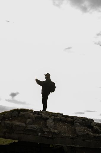 An adult hiker with a backpack taking a picture of the scenery with a phone in Spain
