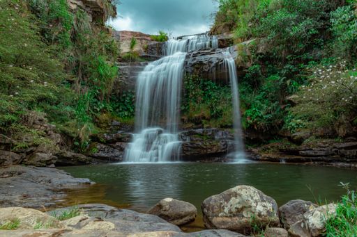 A beautiful shot of a lively waterfall and river surrounded by cliffs and rocks in a green jungle