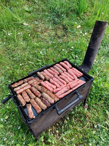 A variety of seasoned meats sizzling on the grates of an outdoor barbecue grill, creating a delicious aroma