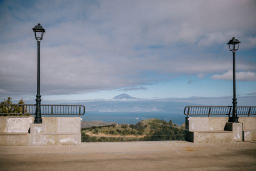 A scenic road leading to a tranquil beach surrounded by a majestic mountain in the background